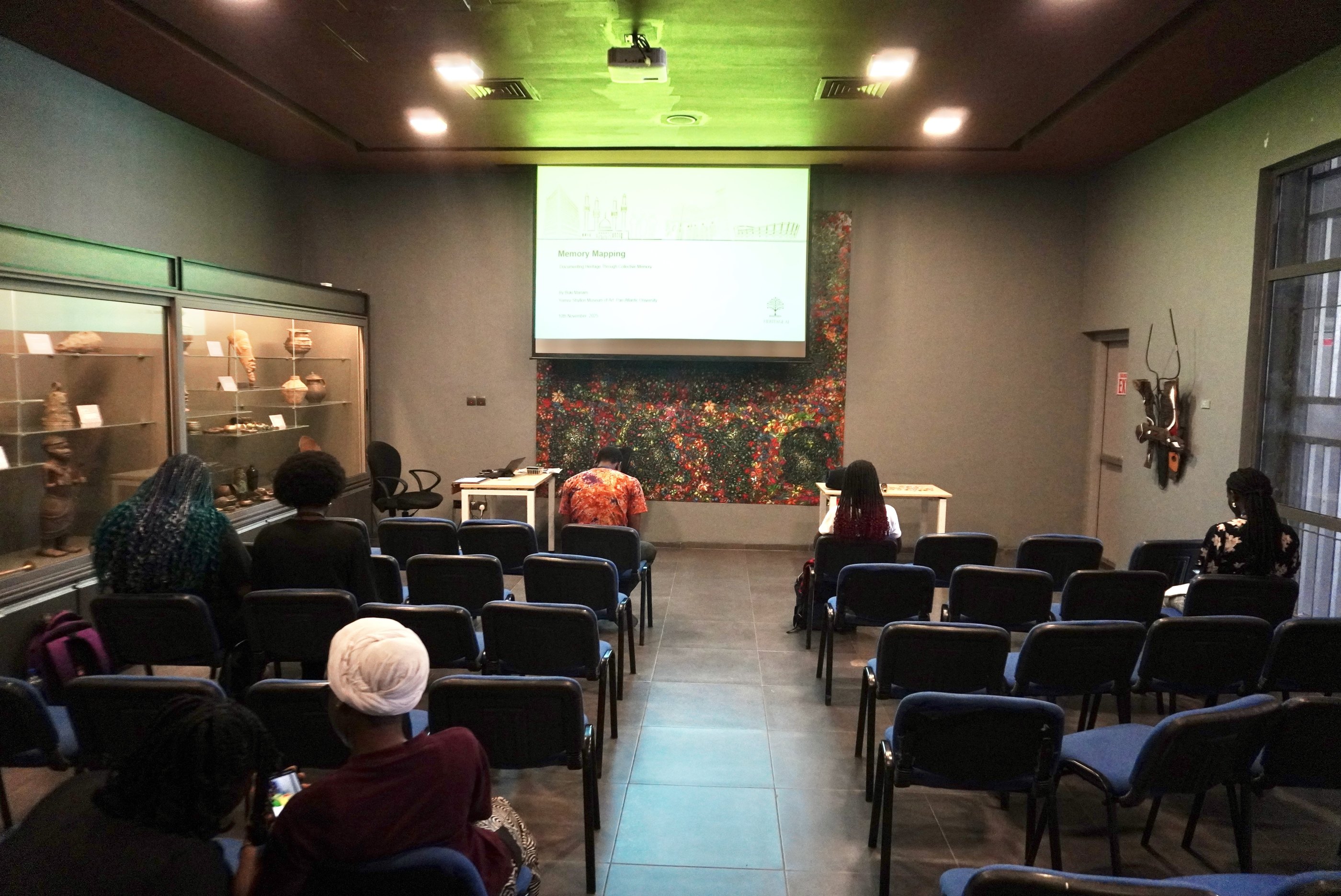 Participants seated in rows facing a projected screen in a museum gallery room